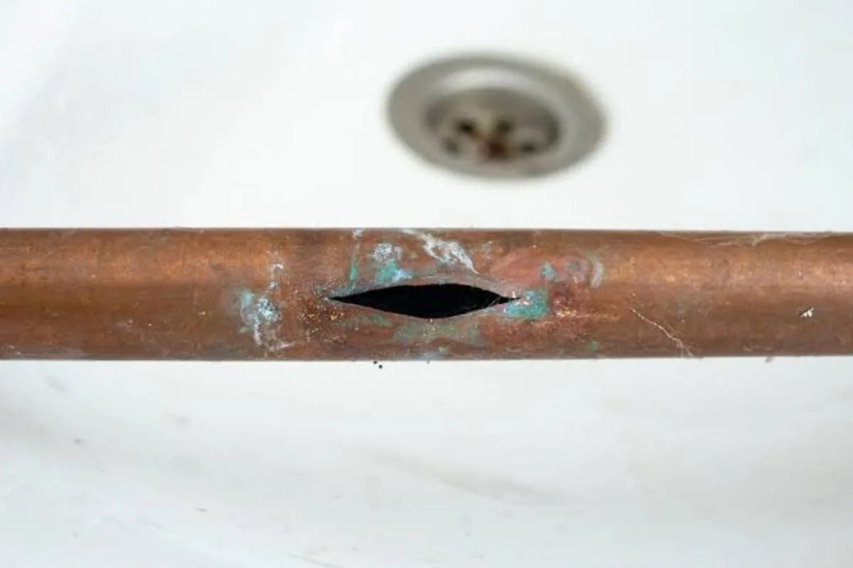 Copper pipe exposed under a slab with the leak point circled