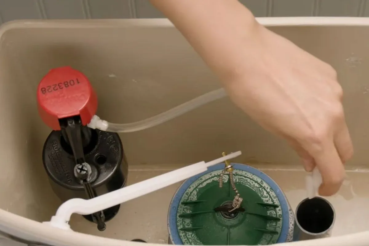 Toilet tank open showing the flapper and fill valve